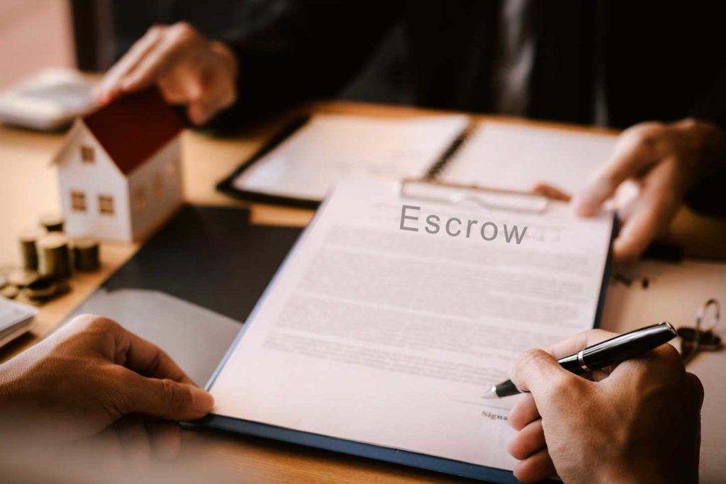 Hands of two people doing a transition, signing papers across a desk