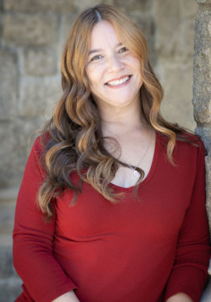 Jennifer Underhill leaning up again a wall smiling