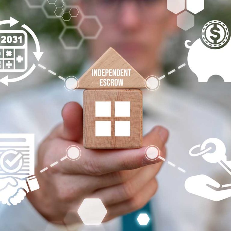 Man's hand holding a little wooden house with "Independent Escrow" written on it