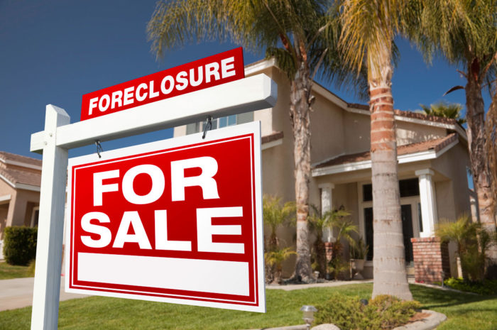 Foreclosure and for sale sign in front of a house.