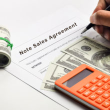 A person's hand filling out loan documents.