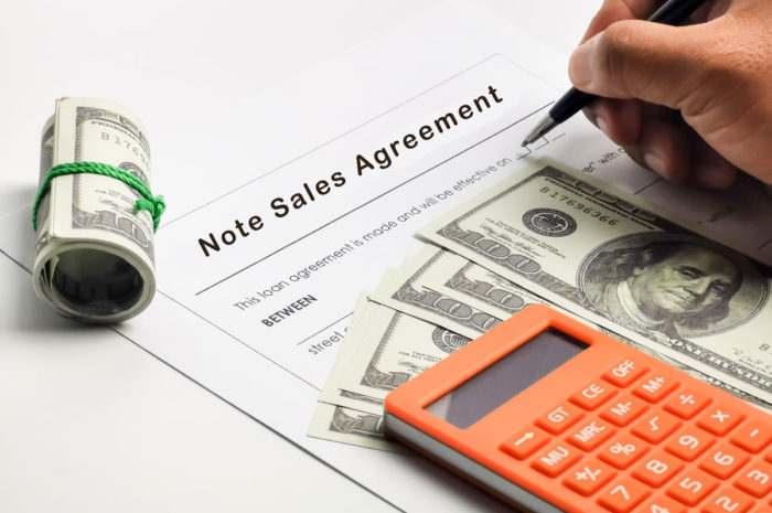 A person's hand filling out loan documents.